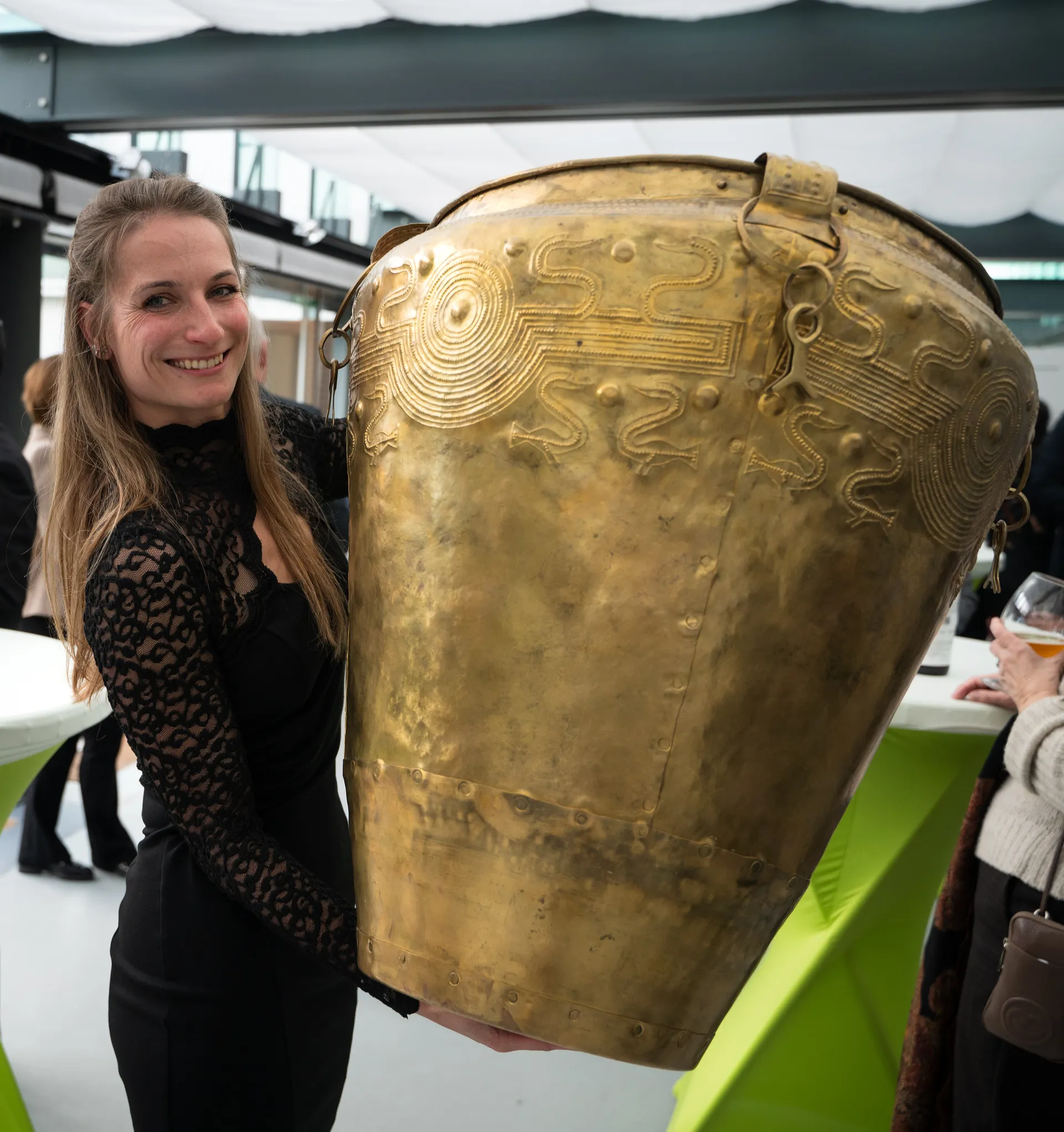Die Archäologin Tereza Jošková hält einen großen verzierten Eimer aus Bronzeblech..