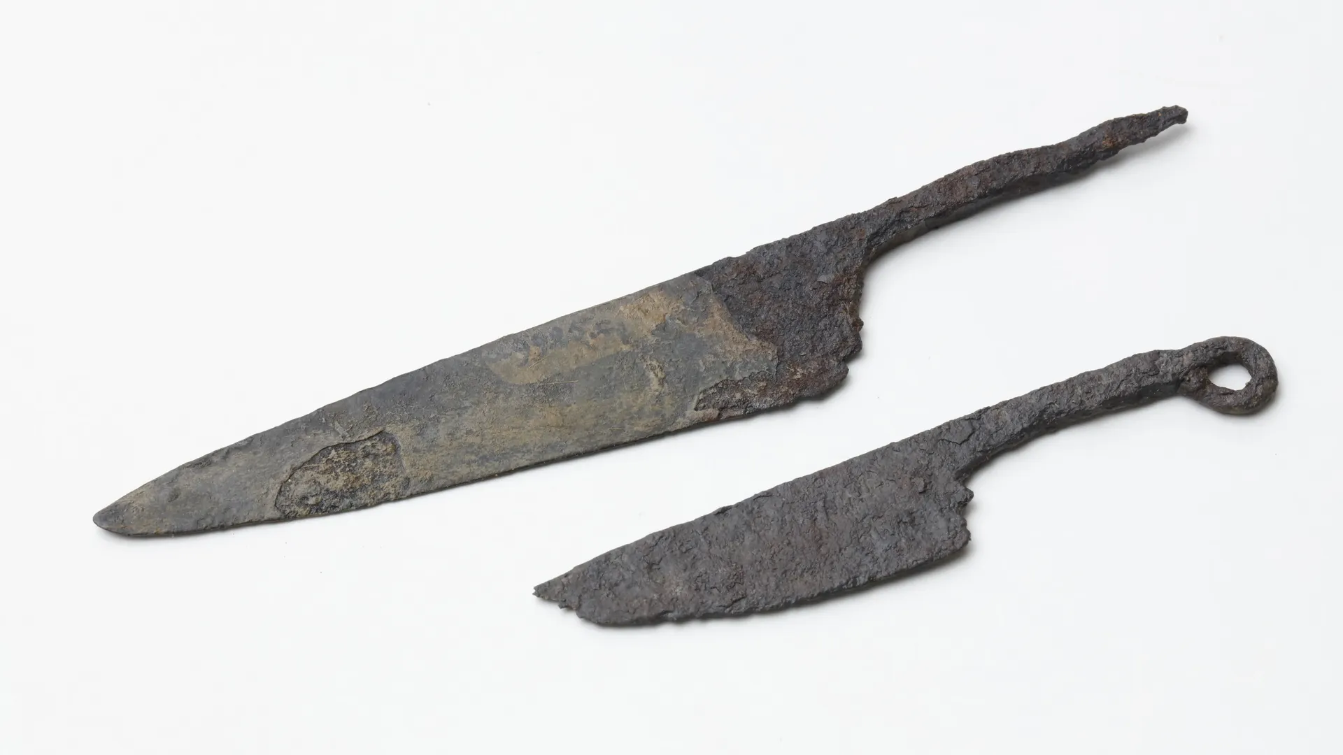 Zwei silberne Messer aus Eisen mit unregelmäßiger Oberfläche. Bei einem der Messer ist die Spitze abgebrochen.