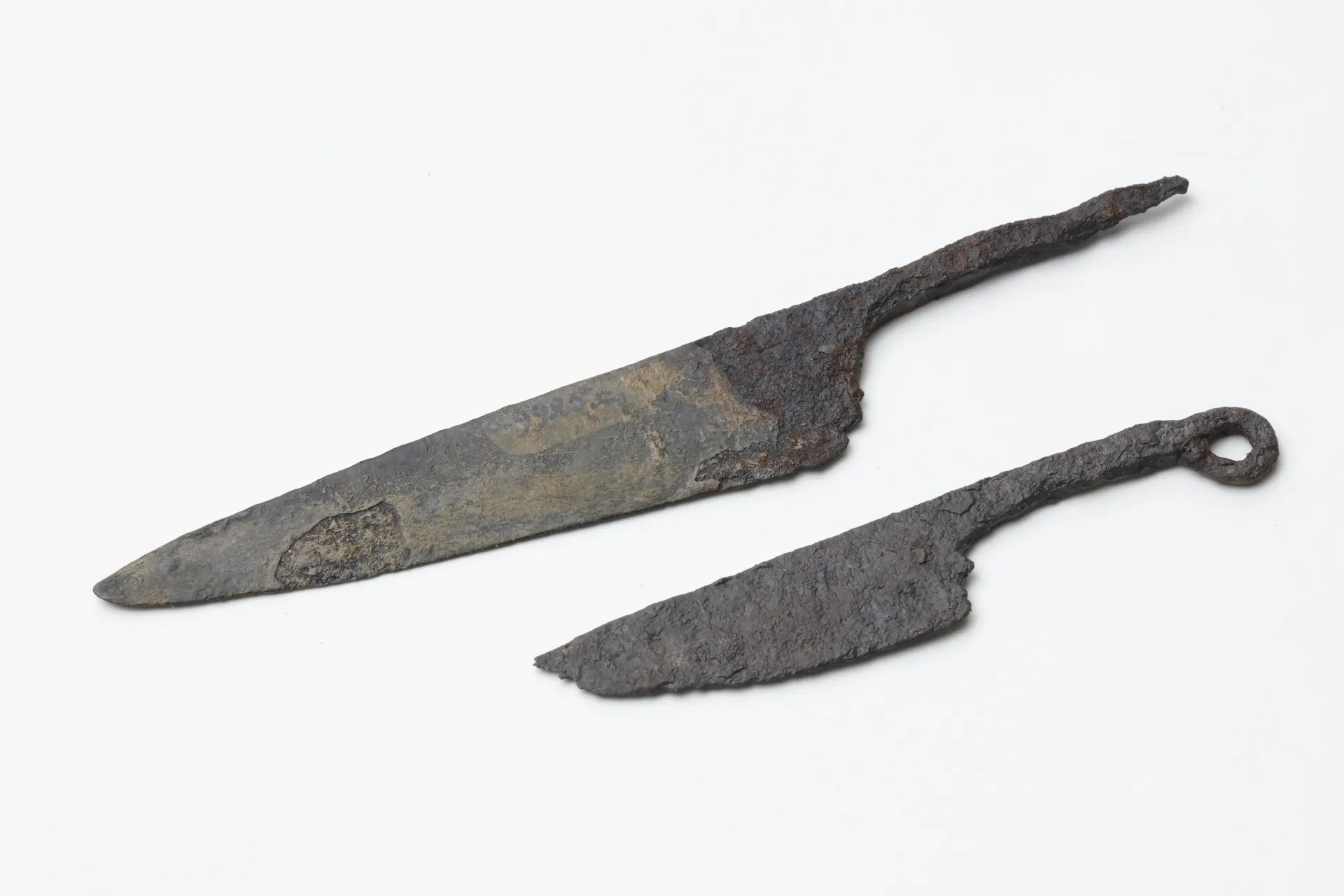 Zwei silberne Messer aus Eisen mit unregelmäßiger Oberfläche. Bei einem der Messer ist die Spitze abgebrochen.